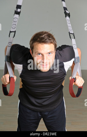 Un uomo utilizza gli anelli di sospensione Foto Stock