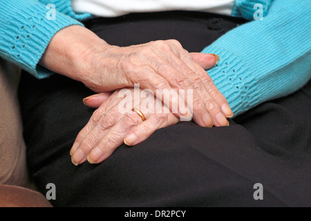 Vecchia Signora con una mano sopra l'altra in appoggio sul suo giro anche indossando un oro anello di nozze. Foto Stock