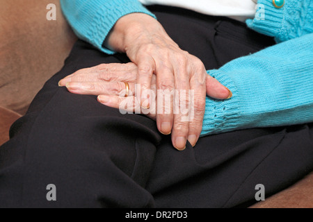 Vecchia Signora con una mano sopra l'altra in appoggio sul suo giro anche indossando un oro anello di nozze. Foto Stock