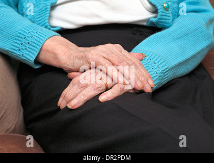 Vecchia Signora con una mano sopra l'altra in appoggio sul suo giro anche indossando un oro anello di nozze. Foto Stock