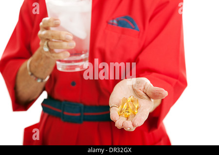 Donna Senior assunzione di omega 3 olio di pesce di capsule per la salute. Primo piano con il focus sull'olio di pesce nella sua mano. Foto Stock