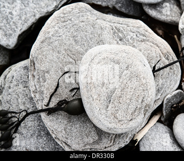 Piccola pila di ciottoli e di alghe sulla spiaggia di Ardmair, Highlands Scozzesi. Foto Stock