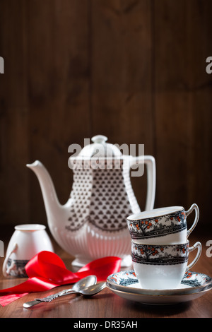 Teacups e piattini con teiera in ambiente rustico Foto Stock