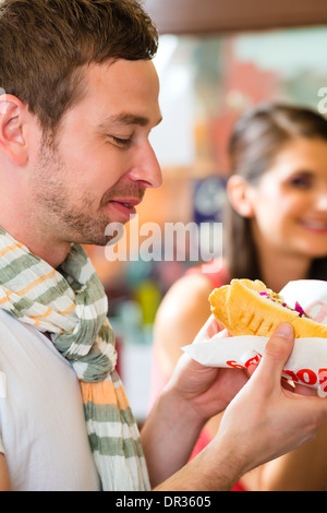 Hotdog - i giovani clienti in uno snack bar mangiare delizioso fast food salsicce Foto Stock