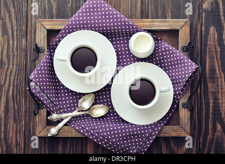 Caffè in tazze con il cucchiaio e il latte sulla vintage vassoio in legno Foto Stock