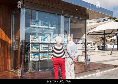 Anziani pensionati giovane in pensione alla ricerca di immobili in vendita e in affitto a un agente immobiliare della finestra in Puerto Calero, Lanzarote, Isole Canarie Foto Stock