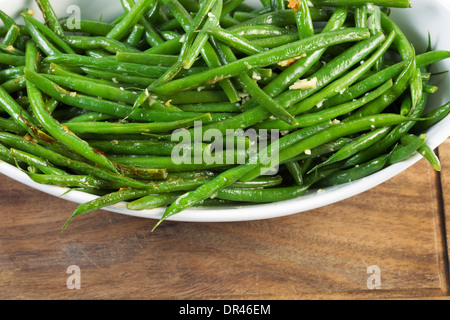 Foto orizzontale di cucinati freschi fagioli verdi in vaso bianco su nero noce scheda servente Foto Stock