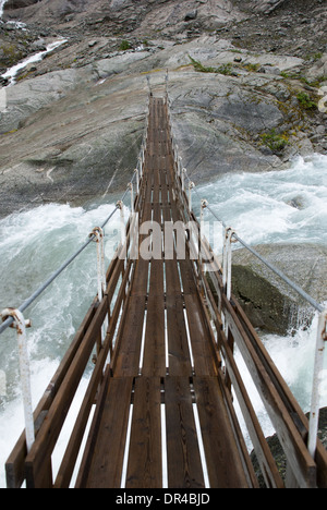 Una piccola tavola ponte che conduce su un fiume torrenziale Foto Stock