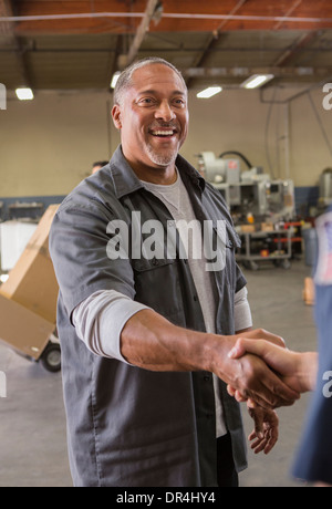 I lavoratori si stringono la mano in magazzino Foto Stock