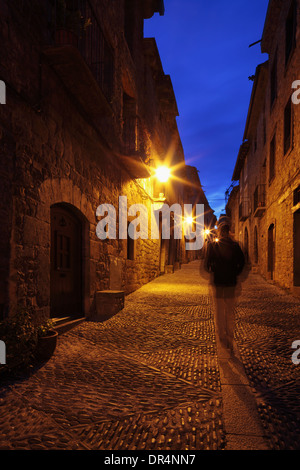Passeggiate turistiche lungo strade acciottolate di Ainsa di notte Foto Stock