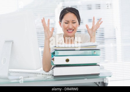 Imprenditrice arrabbiato grida con la pila di cartelle al desk Foto Stock