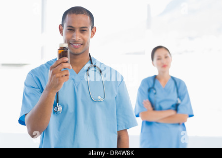 Sorridente medico tenendo una bottiglia di pillole con un collega Foto Stock