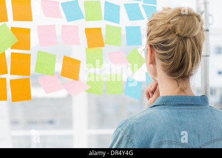 Vista posteriore di un artista femminile guardando colorato sticky notes Foto Stock