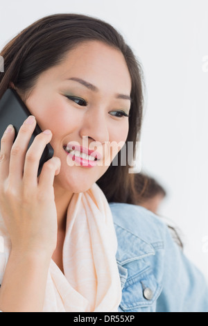 Bella casual donna giovane utilizzando il telefono cellulare in ufficio Foto Stock