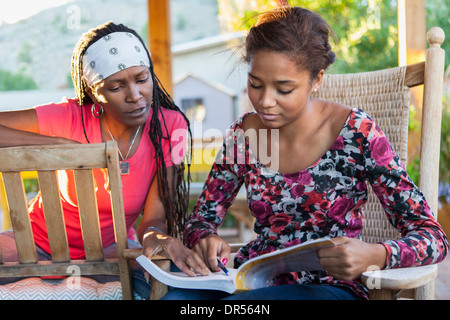 Madre aiutare figlia con compiti sul patio Foto Stock