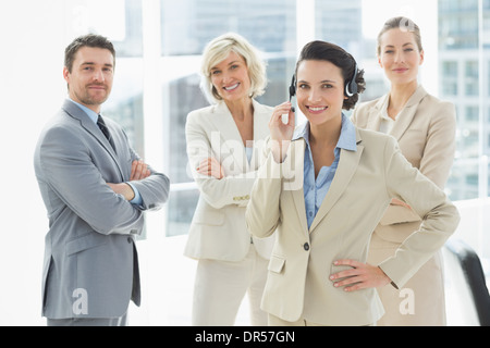 Imprenditrice che indossa la cuffia con i colleghi in ufficio Foto Stock