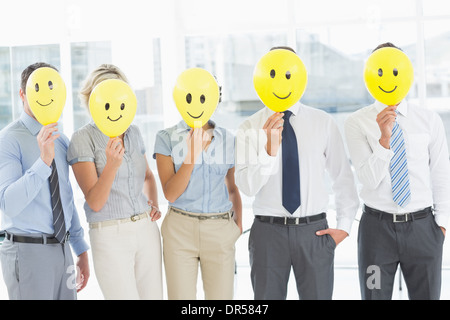 La gente di affari azienda felice sorride davanti delle facce Foto Stock