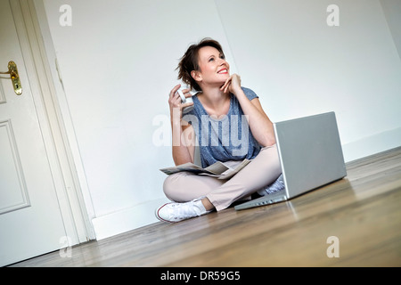 Giovane donna prende una pausa caffè, laptop in primo piano, Monaco di Baviera, Germania Foto Stock