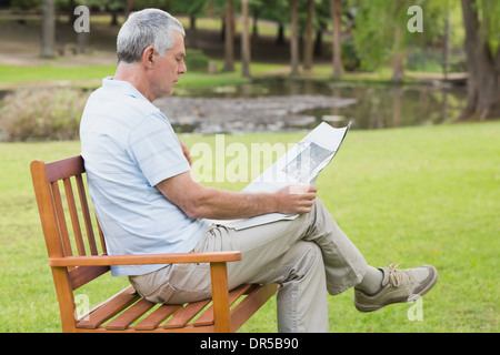 Senior rilassato uomo quotidiano di lettura in posizione di parcheggio Foto Stock