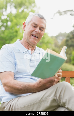 Senior uomo leggendo un libro in posizione di parcheggio Foto Stock