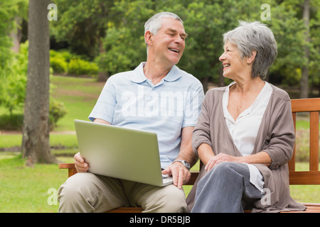 Allegro coppia senior utilizzando computer portatile presso park Foto Stock
