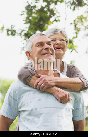 Senior donna abbracciando l uomo dal di dietro Foto Stock