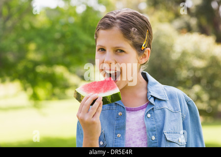 Sorridente ragazza giovane mangiando angurie in posizione di parcheggio Foto Stock