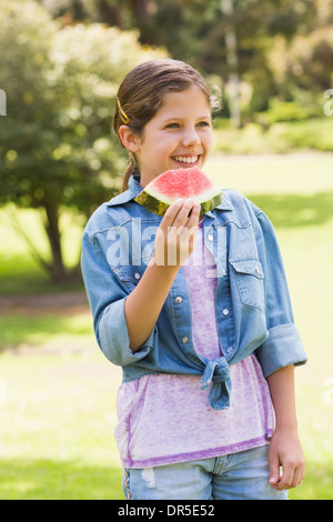 Sorridente ragazza giovane mangiando angurie in posizione di parcheggio Foto Stock