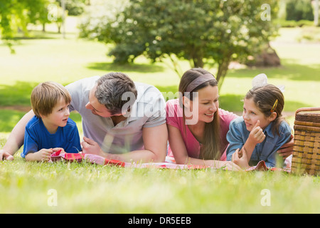 Sorridente giovane con bambini sdraiati sull'erba in posizione di parcheggio Foto Stock