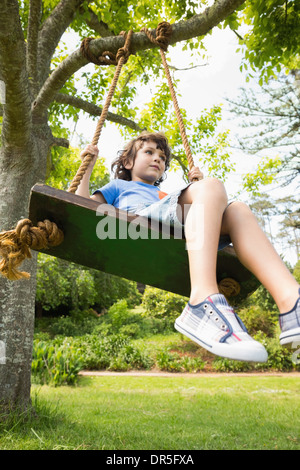Basso angolo di visione di un simpatico ragazzino su swing Foto Stock