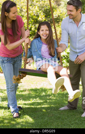 Coppia felice spingendo la figlia per rotazione Foto Stock