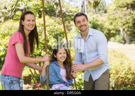 Coppia felice spingendo la figlia per rotazione Foto Stock