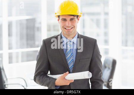 Felice architetto azienda blueprint sorridente in telecamera Foto Stock