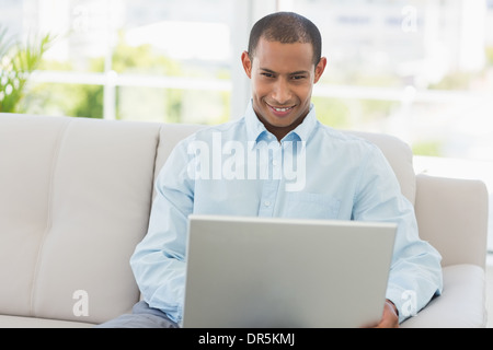 Imprenditore sorridente lavorando sul computer portatile sul lettino Foto Stock