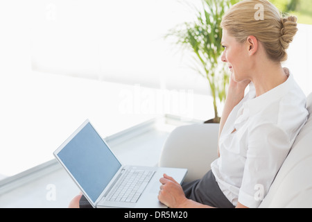 Imprenditrice seduta sul divano lavorando sul computer portatile Foto Stock