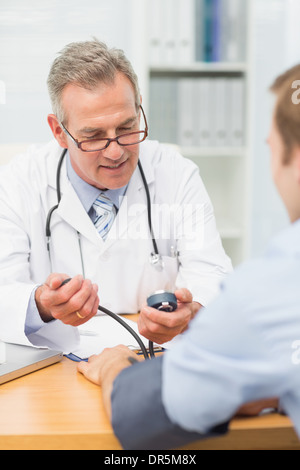 Sorridente medico tenendo i suoi pazienti la pressione sanguigna Foto Stock