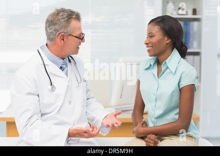 Medico di parlare con allegro paziente giovane Foto Stock