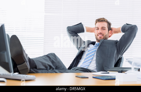 Rilassata imprenditore fiducioso seduta con le gambe sulla scrivania Foto Stock