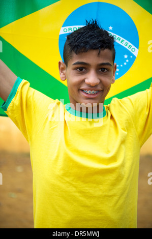 Orgogliosa patriottica brasiliano giovane tifoso indossando i colori nazionali con in mano una bandiera brasiliana Foto Stock