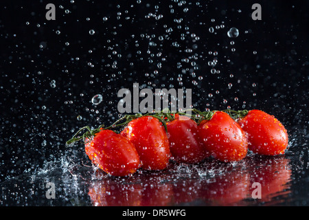 I pomodori di spruzzi d'acqua su sfondo nero Foto Stock