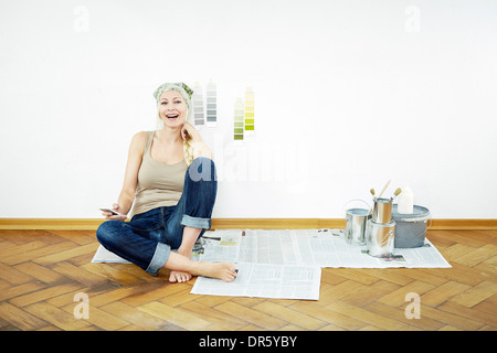 La donna si siede sul pavimento in parquet, i campioni di colore sulla parete, Monaco di Baviera, Germania Foto Stock