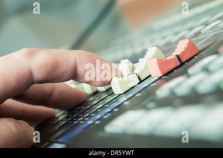 DJ mano spostando i cursori su mixer, close up shot incentrata sul centro dell'immagine Foto Stock
