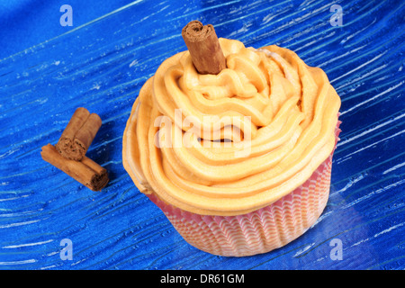 La carota e la cannella cupcake su un piatto di vetro su uno sfondo blu. Foto Stock