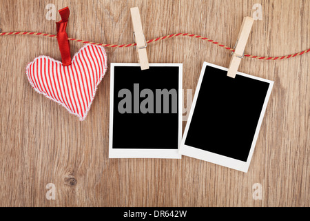 Vuoto foto istantanea e cuore rosso appeso. Su sfondo di legno Foto Stock