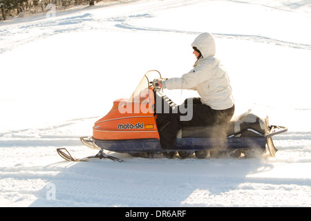 Una donna nel suo inizio 30s godendo di un tratto in snowmobile dopo una nevicata fresca in Quebec, Canada. Foto Stock