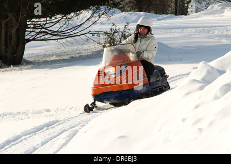 Una donna nel suo inizio 30s godendo di un tratto in snowmobile dopo una nevicata fresca in Quebec, Canada. Foto Stock