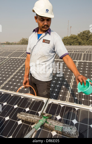 Lavaggio dei lavoratori la polvere fuori i pannelli solari a 1 MW di energia solare stazione gestito da Tata power sul tetto di una società produttrice di energia elettrica Foto Stock