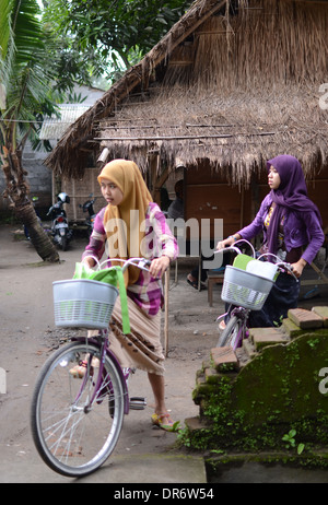 Due studenti Bicicletta Equitazione in strada nel villaggio di Pare. Foto Stock