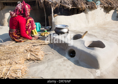 Una donna agricoltore di sussistenza per la cottura su un tradizionale forno di argilla, utilizzando gli steli di riso come biocarburante in Sunderbans, Gange, Delta, India. La zona è molto basso e vulnerabile di innalzamento del livello del mare. Tutte le parti del raccolto di riso sono usati e gli abitanti del villaggio la vita è molto autosufficiente, con una piccola impronta di carbonio. Foto Stock