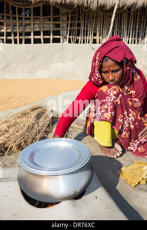 Una donna agricoltore di sussistenza per la cottura su un tradizionale forno di argilla, utilizzando gli steli di riso come biocarburante in Sunderbans, Gange, Delta, in Foto Stock